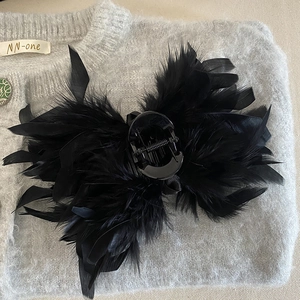 Macro detail of large black hair claw clip with fluffy ostrich feather texture decorations