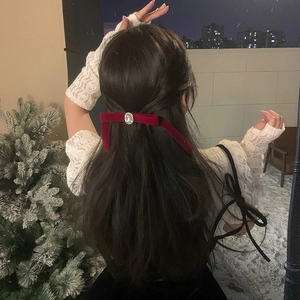 Elegant red velvet bow hair clip with central gemstone on long hair in a snowy winter scene