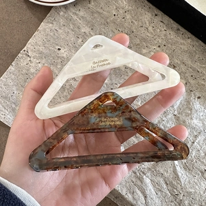 Detail of triangle acetate hair claws in pearl white and tortoiseshell pattern