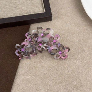 Detail der Haarklammer aus Acetat in Blumenform mit funkelnden lila Strasssteinen