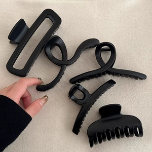 Matte black oversized shark hair claws in various geometric shapes on a beige background