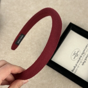 Detail view of burgundy knitted headband featuring textured fabric and handmade label
