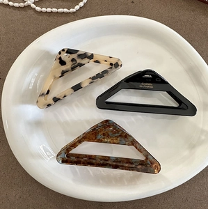 Three acetate hollow triangle hair claws in leopard, black, and marble blue patterns