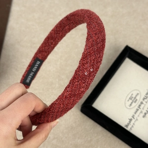 Detail view of red tweed headband showing handmade label and thick woven fabric texture