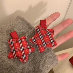 Pair of red and black plaid star hair clips held in hand showing classic British style