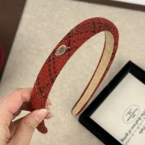 Detail showing the red plaid fabric texture and gold metal logo plaque on the headband