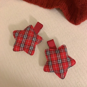 Detail of red plaid star hair clips with soft fabric texture and ribbon-wrapped metal