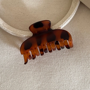 Close-up of a tortoiseshell resin hair claw clip with vintage amber and black patterns