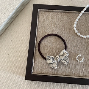 Close-up of marble texture bow hair tie with gold lettering on a linen tray