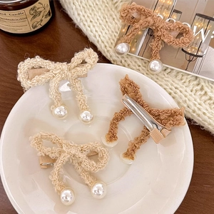 Detailed macro view of lamb wool bow hairpins with elegant faux pearl pendants