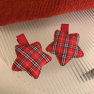 Detail shot of two red plaid star-shaped hair clips with a festive holiday aesthetic