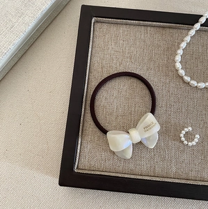 Detail of elegant white pearlescent bow hair tie with gold France Handmade lettering