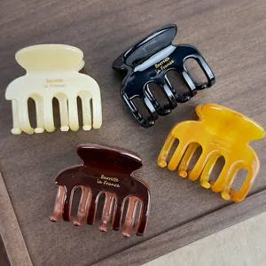 Set of four acetate hair claws in cream, black, amber, and coffee with gold lettering