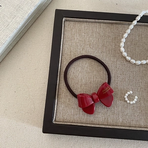 Close-up of red acetate bow hair tie with gold handmade lettering on elegant tray