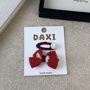 Red velvet bow and white pom pom hair clips set on a handmade white display card