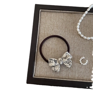 Elegant grey marble acetate bow hair tie with gold lettering on a linen background