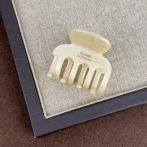Close-up of cream acetate hair claw with gold Barrette La France lettering details