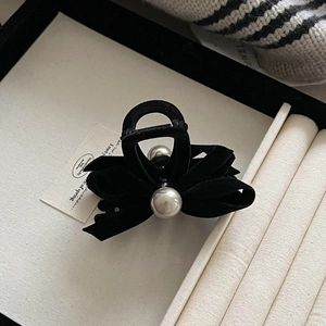 Close-up of black velvet bow hair claw clip with elegant white pearl decorative accents