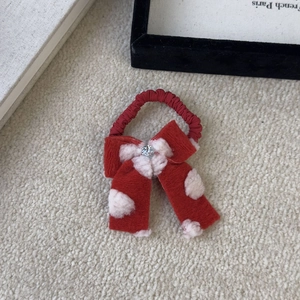 Detailed view of plush red bow hair clip with white dots and crystal center accent