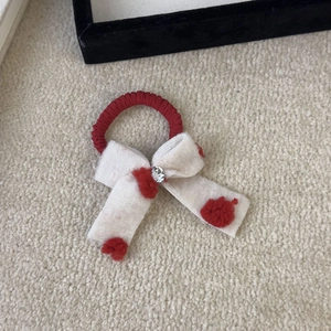 Macro detail of red hair tie with cream plush bow featuring red hearts and a center rhinestone