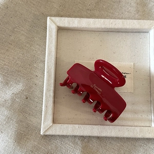 Detailed side view of a dark red acetate hair claw clip with golden France lettering