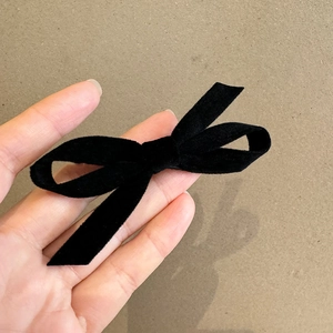 Detail of high-density black velvet bow hair clip with metal fastener in hand