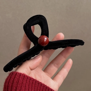 Close-up of black velvet hair claw clip featuring a prominent red pearl bead accent