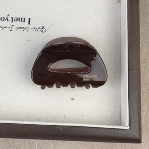 Detail of a tortoiseshell acetate hair claw featuring a gold France Handmade logo print
