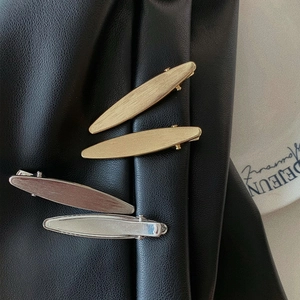 French matte metal leaf hair clips in gold and silver set on black leather background