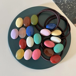 Colorful resin pebble hair clip and elastic tie set displayed on a green round tray