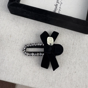 Detail of vintage black velvet bow hair clip with sparkling rhinestones and gold tag
