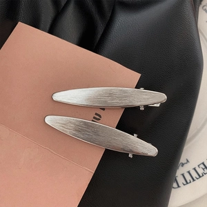 Detailed macro view of two silver matte leaf hair clips with brushed metal texture
