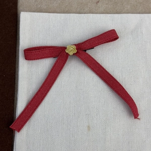 Détail d'un nœud papillon en soie rouge avec rose dorée et pince en métal noir