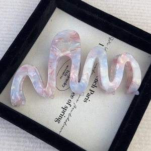Detail of wave acetate hair claw with pink blue marble texture in decorative box