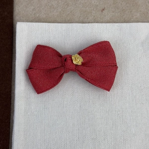 Détail d'une pince à cheveux nœud rouge ornée d'une rose dorée en métal sculpté