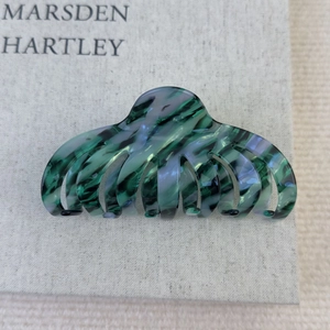 Détail d'une grande pince à cheveux en acétate avec des motifs de marbre vert et noir