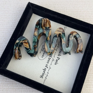 Detailed view of large marble acetate wavy hair claw clip in a gift box packaging