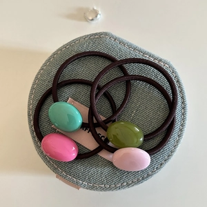 Set of four colorful candy-bead elastic hair ties on a premium blue denim textured surface