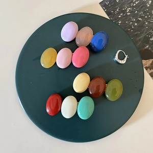 Close-up of candy-colored oval resin hair clips on a dark green decorative tray