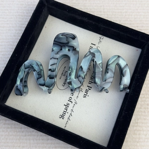 Detailed top view of a large wavy acetate hair claw clip with grey marble pattern