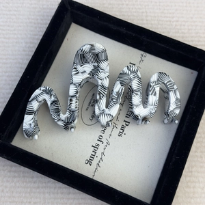 Detail view of large wave acetate hair claw clip with black and white marble pattern