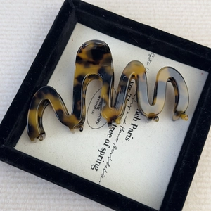 Detail of tortoiseshell wavy hair claw clip in a luxury jewelry presentation box