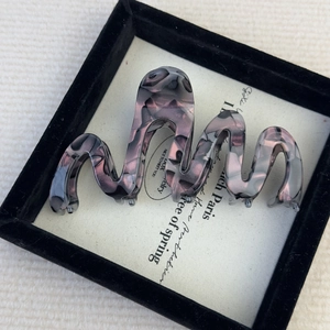 Detailed view of large wavy acetate claw clip with purple leopard texture in display box