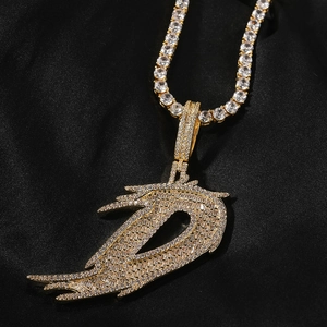 Vue macro du pendentif lettre D hip hop doré avec ailes et zircons sur soie
