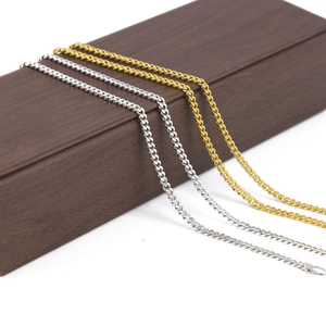 Dettaglio di catene Miami Curb oro e argento su una scatola da esposizione in legno