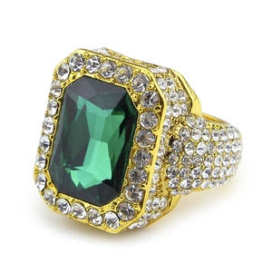Macro detail of iced out gold ring featuring large rectangle green emerald stone