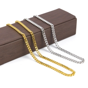 Dettaglio di collane a catena cubana oro e argento su espositore in legno scuro