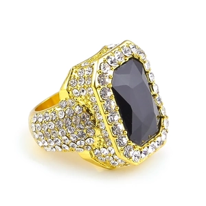Macro view of gold-plated hip hop ring featuring a large black stone and white crystals