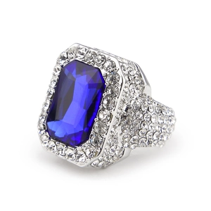 Macro shot of silver hip hop ring featuring a large blue gemstone and micro-pave crystals