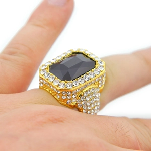 Macro detail of men's wide gold ring with large black gemstone and pave zircon inlay
